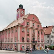 Roze barok stadhuis met klokkentoren op de marktplaats van Eichstätt, omringd door kleurrijke historische gebouwen en fietsers op de kasseien.