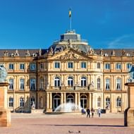Neues Schloss in Stuttgart met gele barokke gevel, sierlijk fronton en twee leeuwenbeelden op sokkels die het voorplein flankeren.