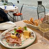 Antipasti bord met vleeswaren, kaas, olijven en kruiden geserveerd met witte wijn en brood op restaurantterras in Alba, Piëmont.