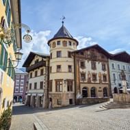 Historisch marktplein in Berchtesgaden met kleurrijke Alpengebouwen, ronde toren met kegeldak, beschilderde gevels en kasseien.
