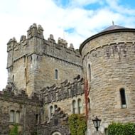 Glenveagh Castle in Ierland Stenen kasteel met kantelen en ronde toren in Glenveagh, Ierland. Klimop groeit op de muren onder een blauwe bewolkte hemel.
