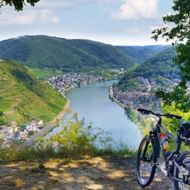 Zwarte fiets geparkeerd op uitkijkpunt over Moezeldal bij Cochem, met terrasvormige wijngaarden op hellingen en stad beneden.
