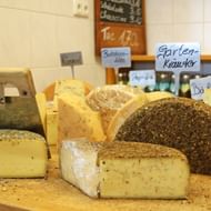 Verschillende regionale kazen op houten toonbank met Duitse labels, waaronder kruidenkaas in de bergkaasmakerij Weizern.