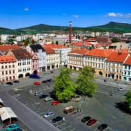 Luchtfoto van het hoofdplein van Litoměřice met kleurrijke barokgebouwen, rode pannendaken, geparkeerde auto's en groene bomen.