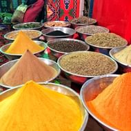 Metalen kommen gevuld met kleurrijke kruiden en specerijen op een Egyptische markt. Heldergele, oranje en bruine poeders naast zaden en gedroogde kruiden.