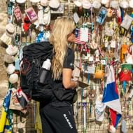 Vrouwelijke pelgrim met zwarte rugzak bekijkt een muur bedekt met schelpen, vlaggen en souvenirs op de Portugese Camino, dag 11.