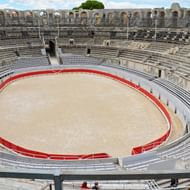 Binnenview van het amfitheater van Arles Binnenview van het oude Romeinse amfitheater van Arles met cirkelvormige arena, rode afscheiding, stenen zitplaatsen en gewelfde galerijen.