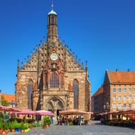 Frauenkirche kerk op Neurenbergs Hauptmarkt met marktkramen. Gotische gevel met sierlijke gevels, klok en toren tegen blauwe lucht.