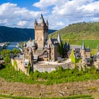Luchtfoto van Reichsburg Cochem, een middeleeuws kasteel met torens en muren op een beboste heuvel boven de Moezel en Cochem.