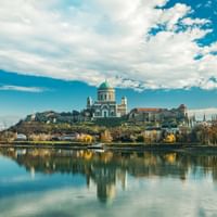 De basiliek van Esztergom met haar groene koepel troont op een heuvel boven de Donau, met perfecte reflecties in het kalme water.