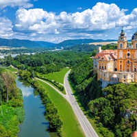 Luchtfoto van de abdij van Melk, een barok klooster met oranje gevel en twee torens, op een rots boven de Donau in de Wachau, Oostenrijk.