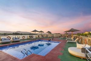 Zonnedek zwembad op Nebu cruiseschip in Egypte met ligstoelen, parasols en uitzicht op de Nijl bij zonsondergang.