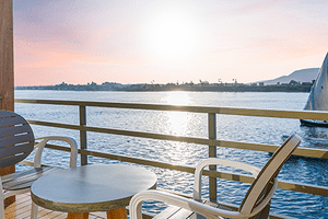 Uitzicht vanaf Nebu schip balkon in Egypte met witte stoelen en tafel met uitzicht op de Nijl met traditionele zeilboot en verre kustlijn.