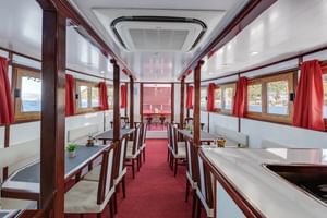 Interieur van MS Mirabela scheepsrestaurant met witte banken, donkere houten tafels, rode gordijnen en ramen met uitzicht op de Kroatische kust.