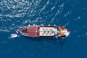 Luchtfoto van cruiseschip MS Mirabela varend in diepblauw Kroatisch water. Het schip heeft een wit-rode romp met ligbedden op het dek.