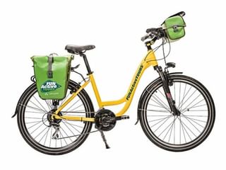 Gele lage instap fiets met laag frame, zwarte wielen en groene Vaude fietstassen op bagagedrager en stuur. Fun Active Tours logo zichtbaar.