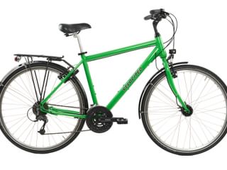 Groene toerfiets met zwart zadel, bagagedrager, voor- en achterlicht en 27-versnellingssysteem tegen witte achtergrond.