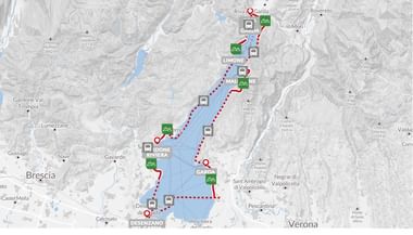 Kaart met een fietsroute gemarkeerd met rode stippellijn rondom het Gardameer, Italië. Route loopt door plaatsen als Riva, Limone, Gargnano en Desenzano.