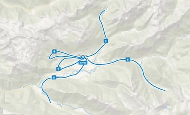 Topografische kaart met blauwe fietsroutes die vanuit Bovec door bergachtig terrein lopen, met meerdere dagtochten gemarkeerd.