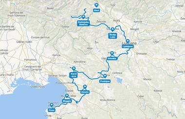 Kaart met fietsroute door Slovenië van Bled naar Piran via Ljubljana, Škofja Loka, Divača en Muggia, gemarkeerd met blauwe lijn en pins.