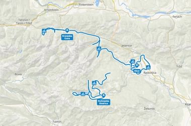 Kaart met blauwe fietsroute door bergachtig gebied, die locaties zoals Kranjska Gora, Bled en Bohinjska Bistrica verbindt.