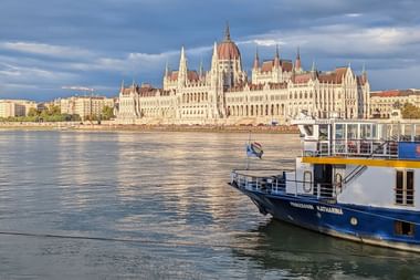 Riviercruiseschip MS Princess Katharina op de Donau met het Hongaarse parlementsgebouw op de achtergrond onder bewolkte luchten.