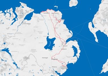 Kaart van Noord-Ierland met een rood gestippelde wandelroute die Bushmills, Ballycastle, Cushendall, Banbridge en Mourne Mountains verbindt.