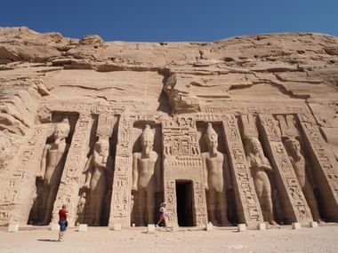 Oude Abu Simbel tempelfacade uitgehouwen in zandsteenrots met vier kolossale zittende beelden en hiërogliefen onder blauwe hemel.