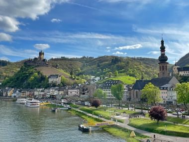 Haven van Cochem met boten op de Moezel, met de historische stad met kerktoren en kasteel Reichsburg op de heuvel.