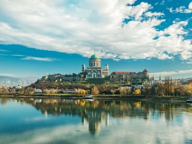 De basiliek van Esztergom met haar groene koepel troont op een heuvel boven de Donau, met perfecte reflecties in het kalme water.