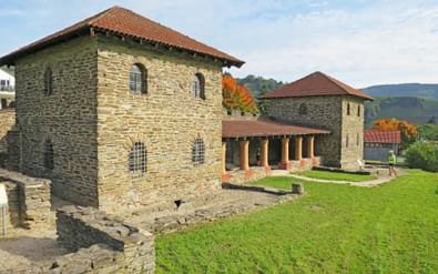 Gereconstrueerde Romeinse Villa Rustica in Mehring met stenen muren, rode pannendaken en zuileportiek omgeven door groen gazon.
