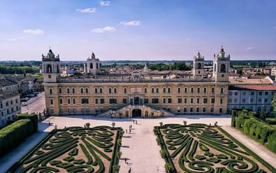 Luchtfoto van het Paleis van Colorno in Emilia met symmetrische barokke tuinen. Het gele paleis heeft twee klokkentorens en sierlijke hagen.