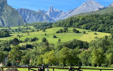 Twee fietsen geparkeerd bij houten hek met uitzicht op groene vallei met dramatische kalksteenpieken van Picos de Europa in Asturië, Spanje.