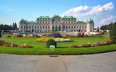 Belvedere Paleis met baroktuinen Wenen Belvedere Paleis in Wenen met groene koperen koepels en barokarchitectuur, omgeven door formele tuinen met kleurrijke bloembedden.