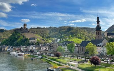 Haven van Cochem met boten op de Moezel, met de historische stad met kerktoren en kasteel Reichsburg op de heuvel.