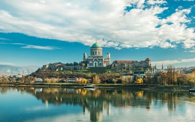 De basiliek van Esztergom met haar groene koepel troont op een heuvel boven de Donau, met perfecte reflecties in het kalme water.