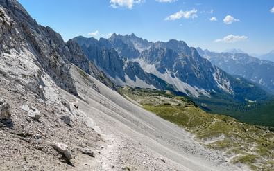 Panoramisch uitzicht vanaf Mandlscharte in het Karwendel met dramatische kalksteenpieken, puinhelling en groene vallei beneden.