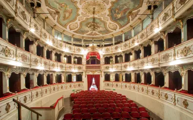 Historisch Teatro Giuseppe Verdi in Busseto met versierd fresco plafond, gelaagde balkons met gouden decoraties en rode fluwelen stoelen.