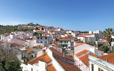Witgekalkt dorp met terracotta daken op heuvel in Portugal. Traditionele huizen op hellingen onder heldere blauwe lucht.