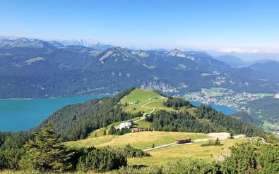 Luchtfoto van Schafbergbahn station op groene bergtop met uitzicht op turquoise meer en Alpenvalleien in Salzkammergut.