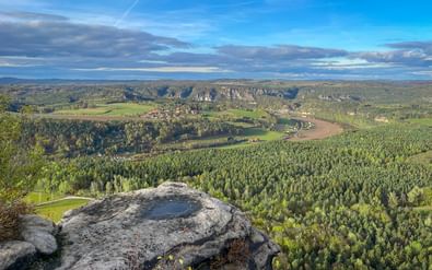 Panoramisch uitzicht vanaf Lilienstein over Elbe-vallei met dichte bossen, zandstenen kliffen en kronkelende rivier door velden.
