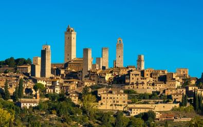 San Gimignano middeleeuwse heuveltop stad in Toscane met kenmerkende stenen torens boven traditionele gebouwen tegen blauwe lucht.
