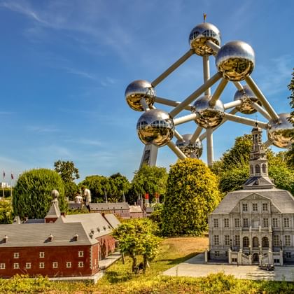 Het iconische Atomium met negen metalen bollen torent boven miniatuurgebouwen in een parkachtige omgeving in Brussel, België.
