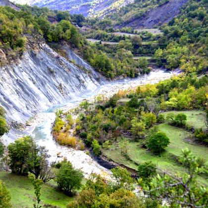Luchtfoto van een kronkelende rivier met witte rotsoevers door Hidden Valley in Albanië, omgeven door groene heuvels en bergen.