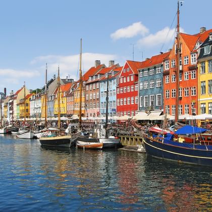 Historische Nyhavn haven in Kopenhagen met kleurrijke 17e-eeuwse herenhuizen langs het kanaal en traditionele zeilboten afgemeerd in het water.