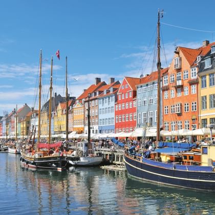 Historische Nyhavn haven in Kopenhagen met kleurrijke 17e-eeuwse herenhuizen langs het kanaal en traditionele zeilboten afgemeerd in het water.