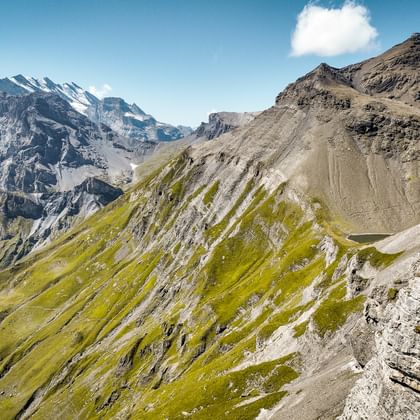 Spectaculair bergpanorama vanaf Schilthorn met besneeuwde toppen, groene alpenhellingen en rotsachtig terrein onder blauwe hemel met wolken.