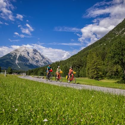 Three cyclists on one of the cycle paths in Leutasch, with a mountain panorama in the background