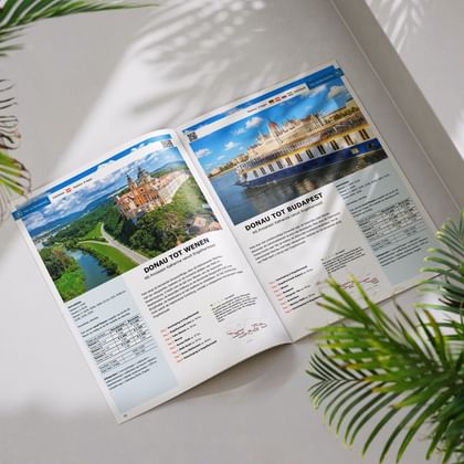 Geopende reisbrochure met twee Donau-fietsroutes: Wenen met abdij Melk en Boedapest met parlementsgebouw aan de rivier.
