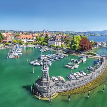 Luchtfoto van Lindau haven aan het Bodenmeer met vuurtoren, jachthaven, historische gebouwen met rode daken en turquoise water.